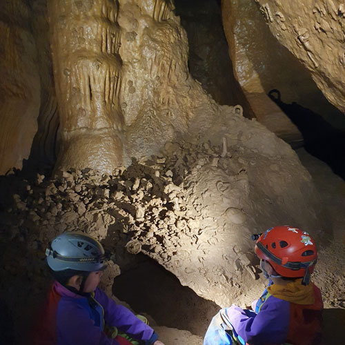 randonnee-souterraine-speleo-famille-ardeche-les-vans-ben-aven-tour-4 Des enfants dans un grotte qui regardent les formations rocheuses